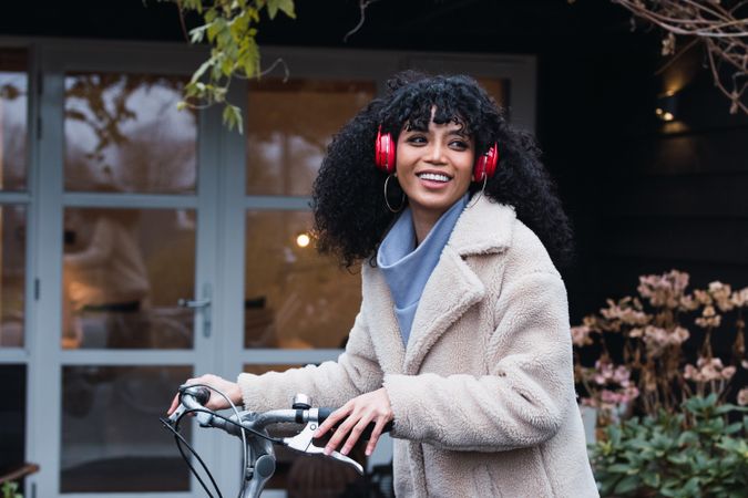 Cheerful Black woman in headphones with bicycle