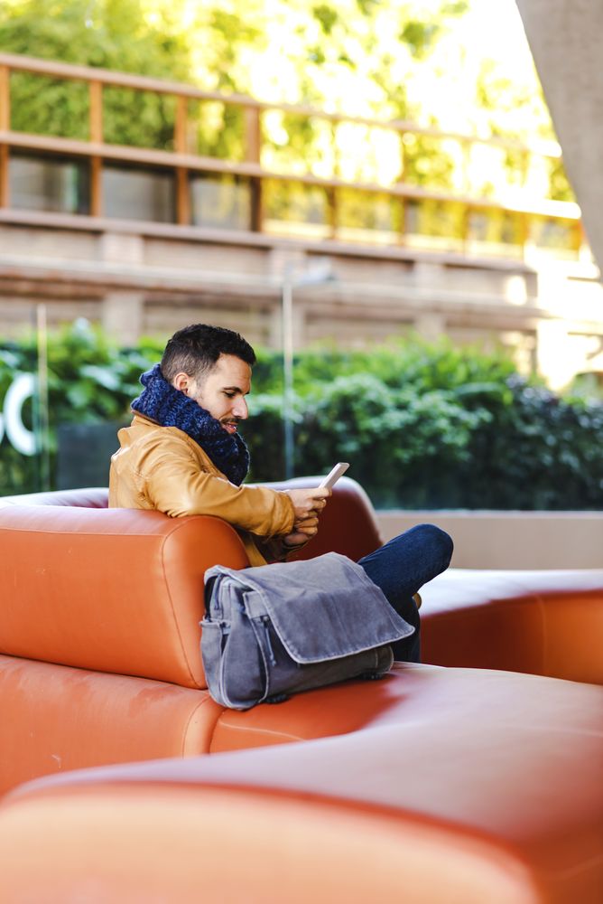 Stylish man using smartphone on couch