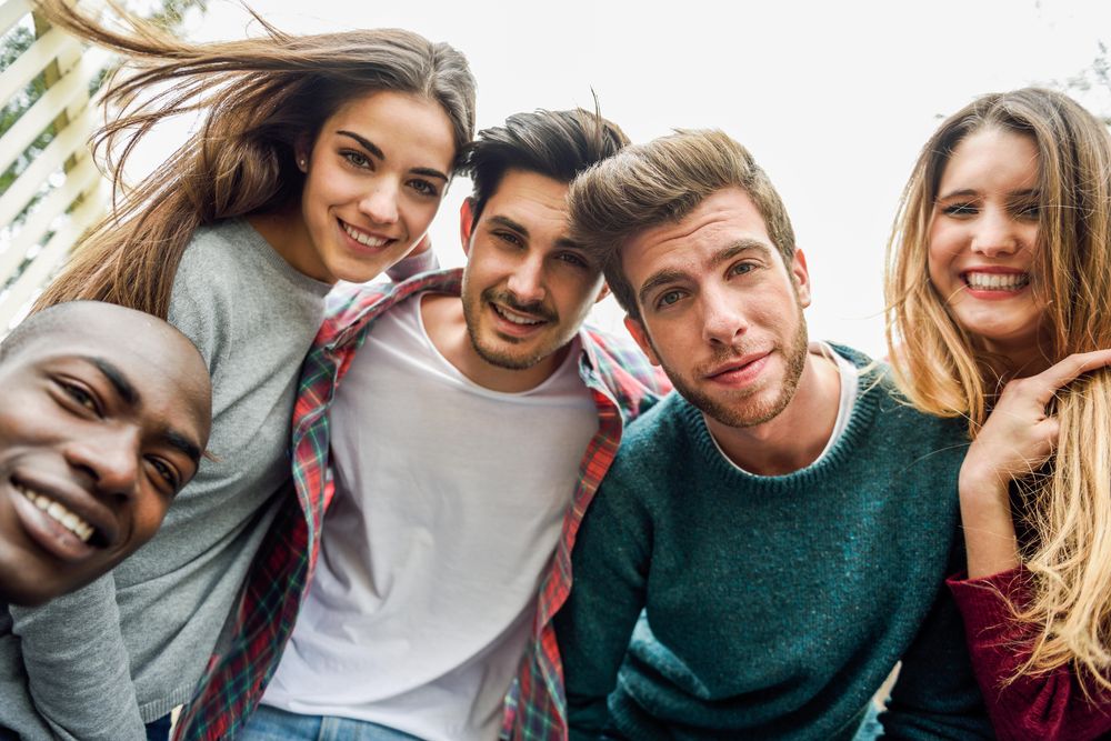 Group of smiling men and women looking down at camera and posing