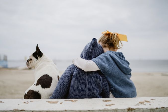 Kids hugging dog on beach