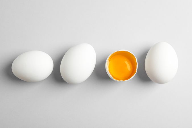 Chicken eggs and half with yolk on light background, space for text