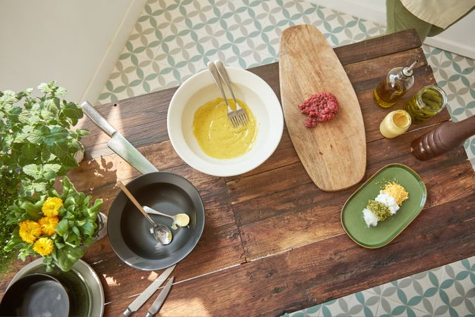 Various ingredients for preparing steak tartare placed on wooden