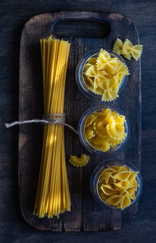 Top view of different pasta shaped on wooden board