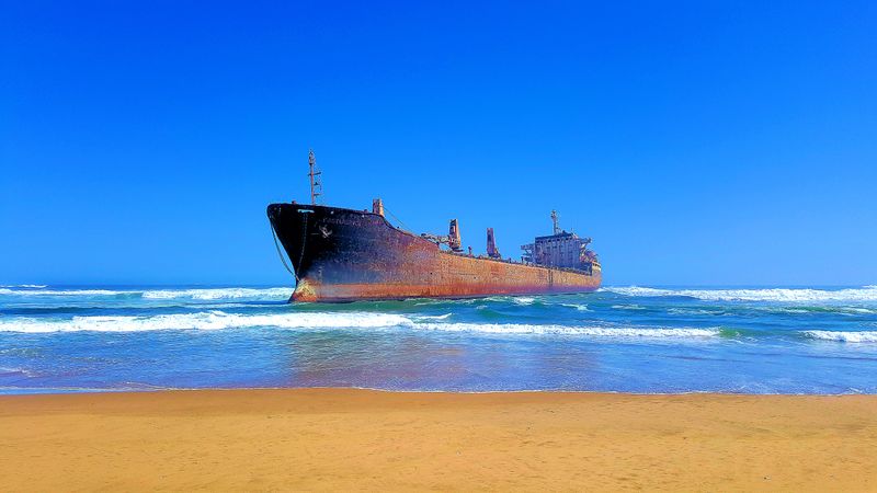 Brown ship on sea under blue sky