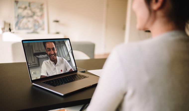 Woman sitting at table having a video call with her husband on laptop