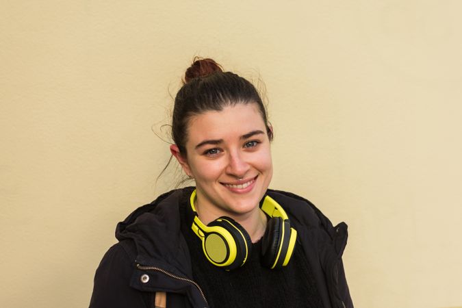 Satisfied young woman smiling while listening to music in earphones