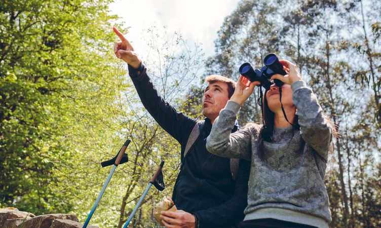 Couple doing trekking looking with binoculars