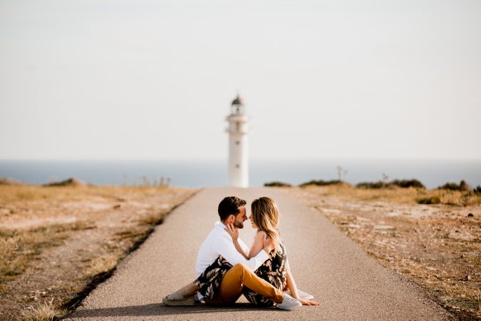 Smiling lovers cuddling on path to sea