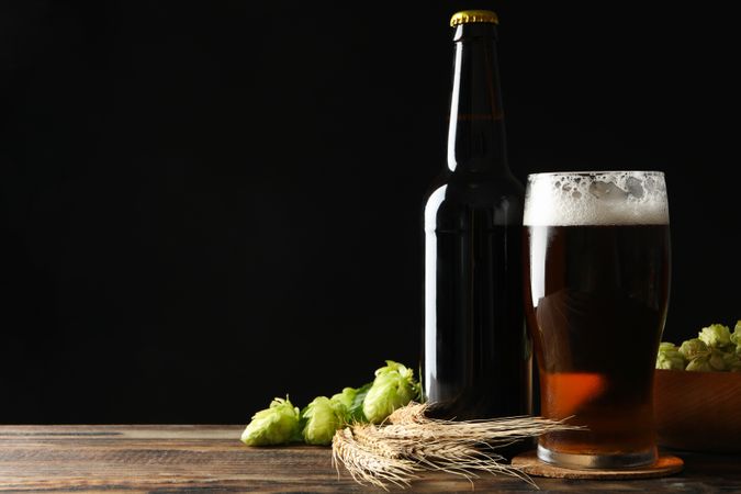 Beer, wheat and hop on wooden table