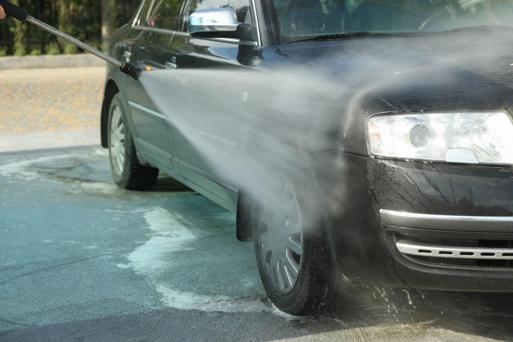 A man washes a car in a manual car wash. Clear car