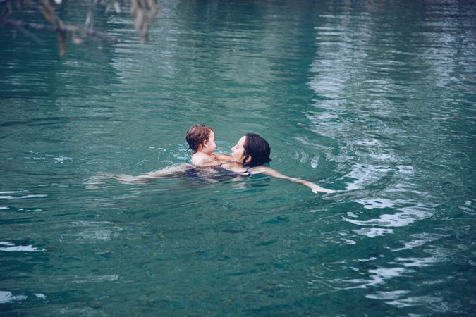 Mother with kid swimming in lake in spa