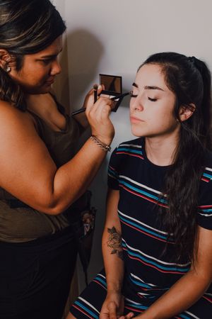 Young woman getting makeup by makeup artist in salon
