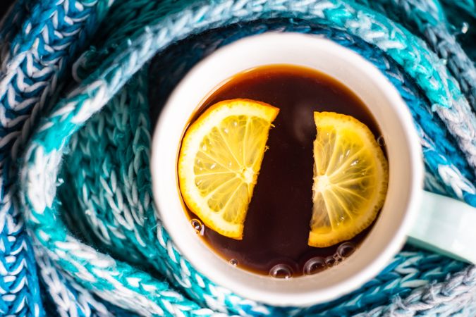 Close up of teal scarf wrapping around cup of tea