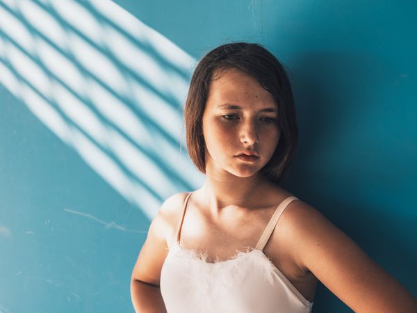 Ballerina standing with sad face near wall