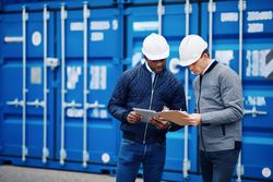 Two men in hardhats focused on plans for a building project