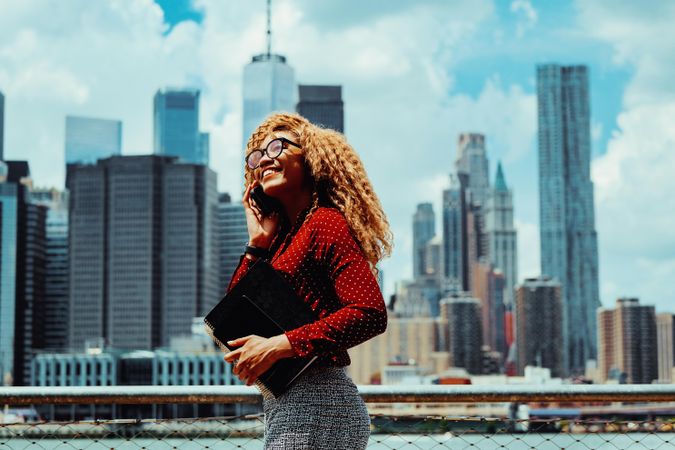 Confident professional Black female holding her notebooks with Manhattan in the background