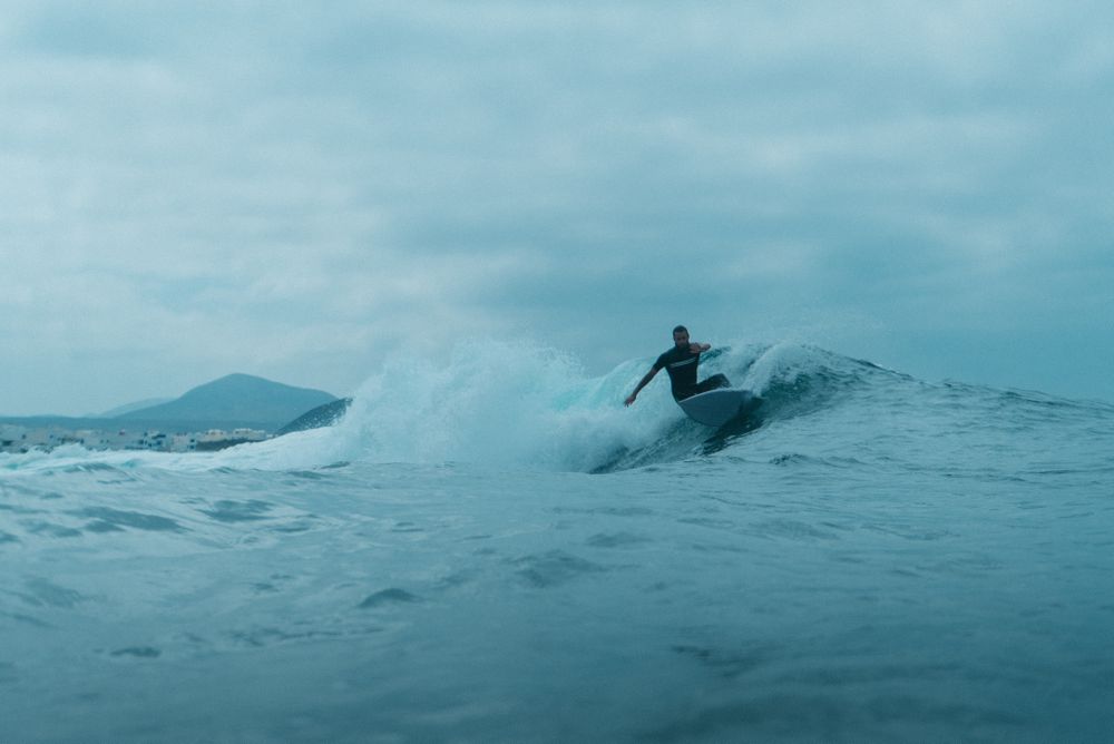 Surfer catching a wave under cloudy sky