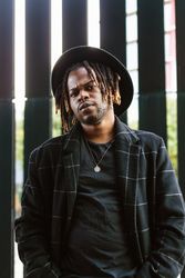 Stylish Black man in hat standing on street