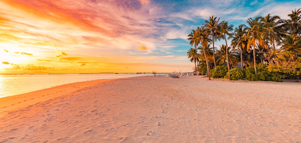 Beach water front under a blue and peach sky at sunset, wide