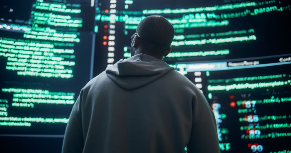 Back View of Young Black Man Looking at Big Digital Screens Glitching While Displaying Code Prompts.