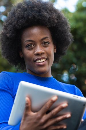 Smiling Black woman browsing tablet in city
