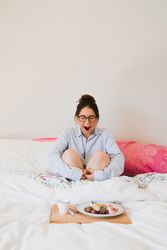 Young woman with breakfast on bed yawning