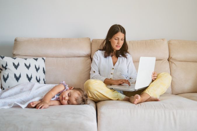 Mother working on netbook near sleeping daughter