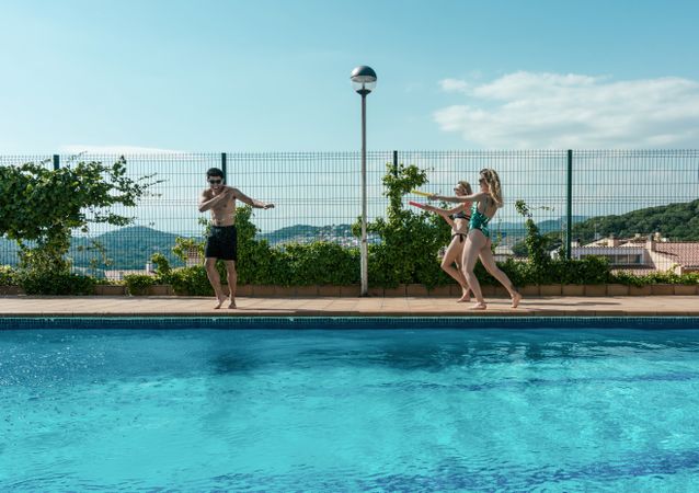 Friends playing with water pistols in the pool