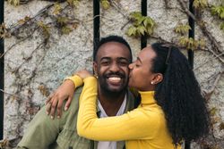 cute Black couple kissing on the cheek and smiling