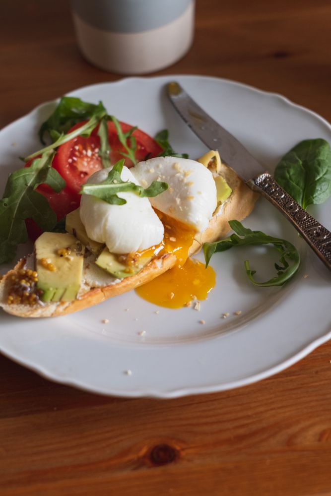 Slice of bread with avocado and runny poached egg on top