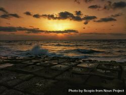 Sea waves crashing on shore during sunset 4dkxn5
