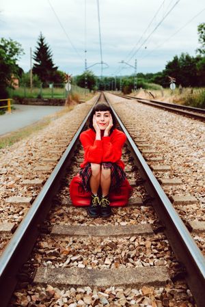 Woman sitting on sleepers in middle of railway
