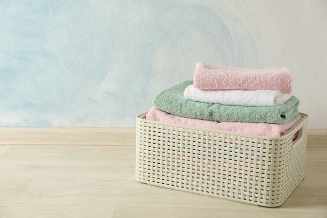 Basket with clean laundry on textured floor, space for text