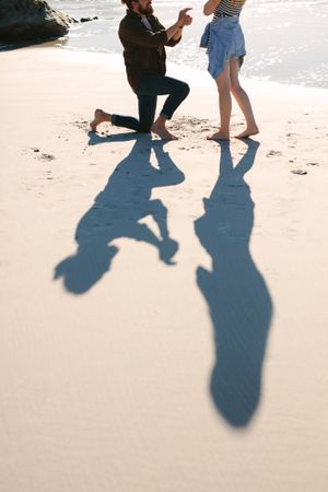 Shadow of  man proposing woman on beach