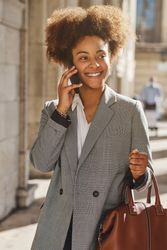 Smiling Black person talking on phone against sunny urban background