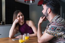 Content couple chatting and having orange juice in kitchen