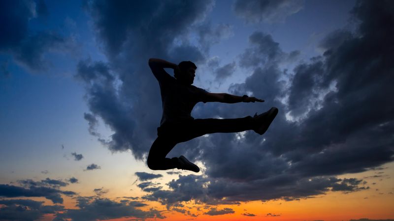Out line of male jumping in kick against a colorful dusk side