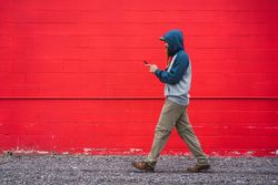 Man using smartphone near red wall