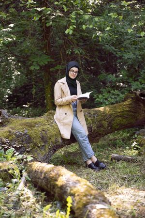Middle Eastern woman relaxing with a book in the forest
