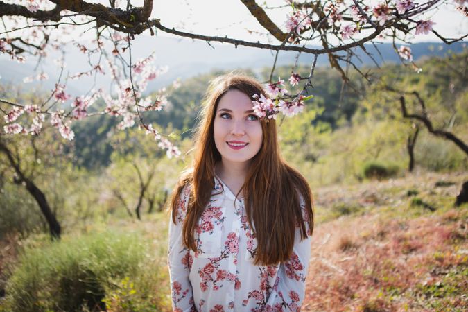 Young happy woman between trees in garden