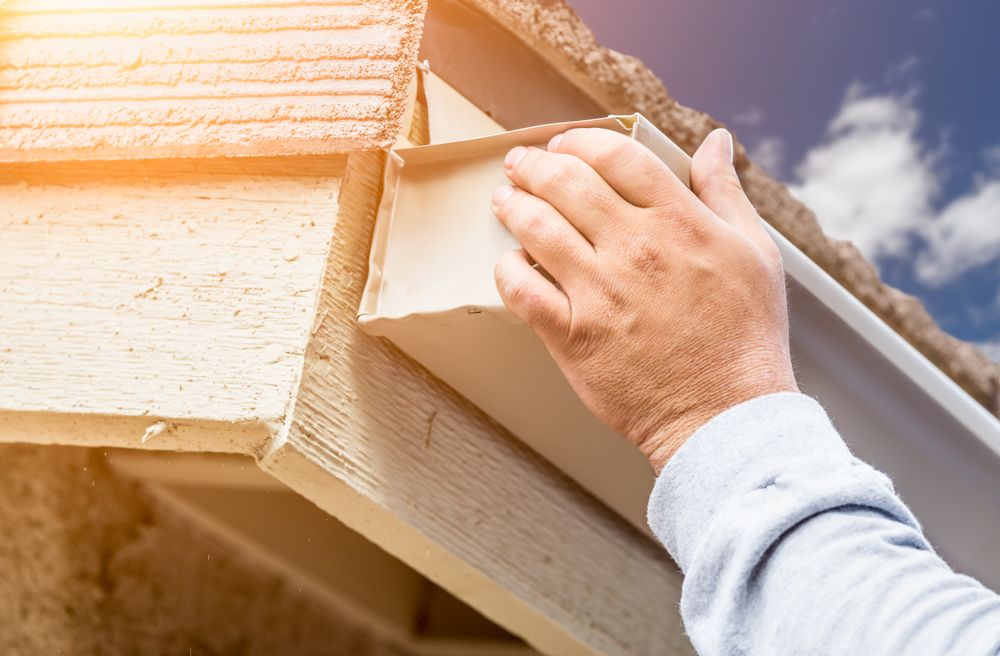Worker Attaching Aluminum Rain Gutter to Fascia of House