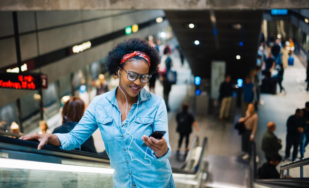 Woman looking at cellphone on escalator exiting the subway