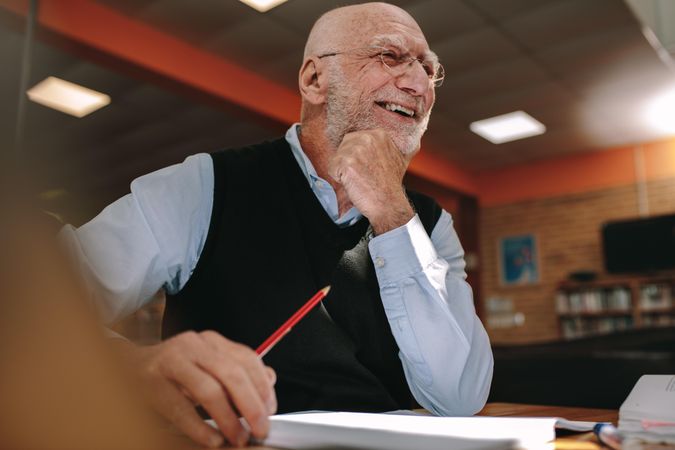 Cheerful older man sitting in classroom listening to lecture