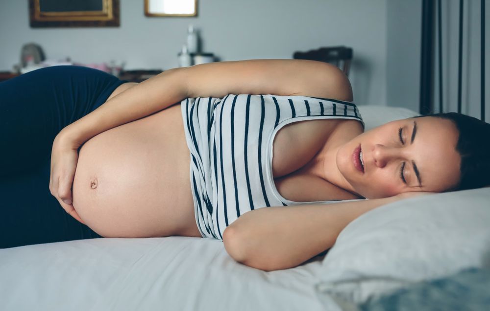 Pregnant woman sleeping in bed