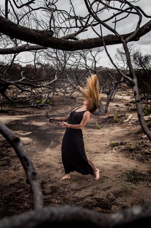 Woman posing on ground near dry trees