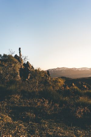 Female traveler standing on mountain slope at sunset