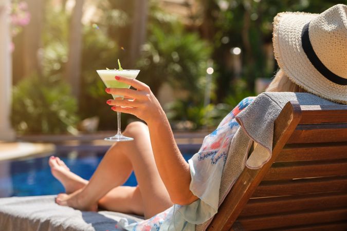 Woman with beverage relaxing on deckchair