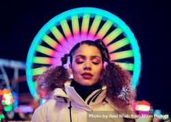 Close up of young woman’s face in front of Ferris wheel lit at night 41lD85