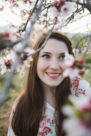 Young happy woman between trees in garden