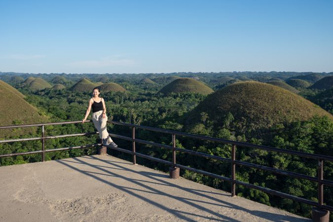 Happy woman standing on observation deck on hill